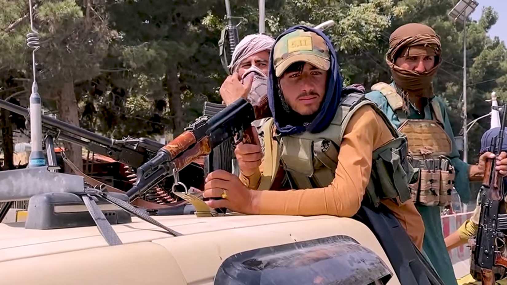 Armed Taliban fighters ride on a captured tan Humvee through Kabul streets on Aug. 17, 2021.